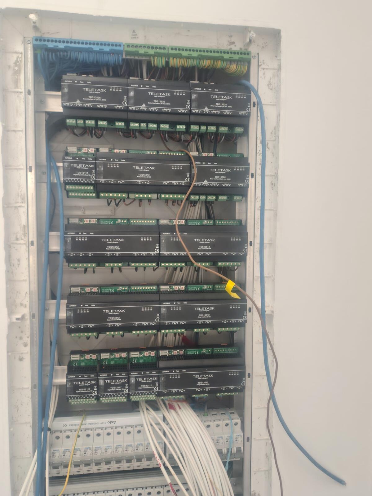 Quadro elétrico de domótica numa moradia, com módulos TELETASK em quatro filas sobre os disjuntores